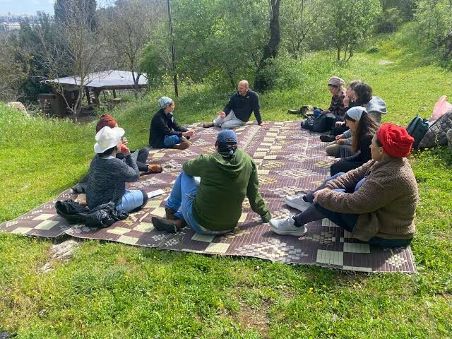People seated together on blankets in a green field